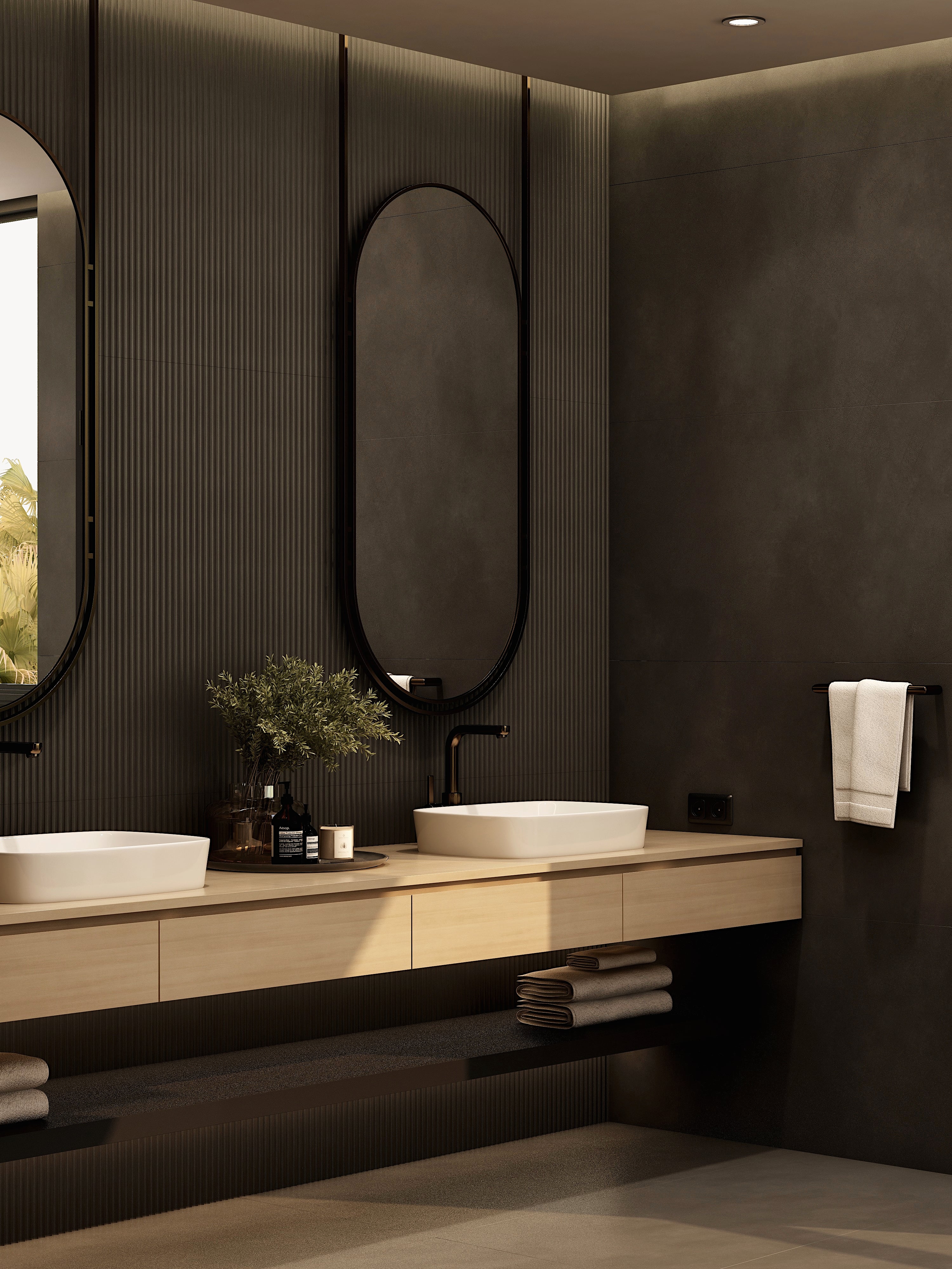 Bathroom vanity viewed from the side beneath an oval mirror.