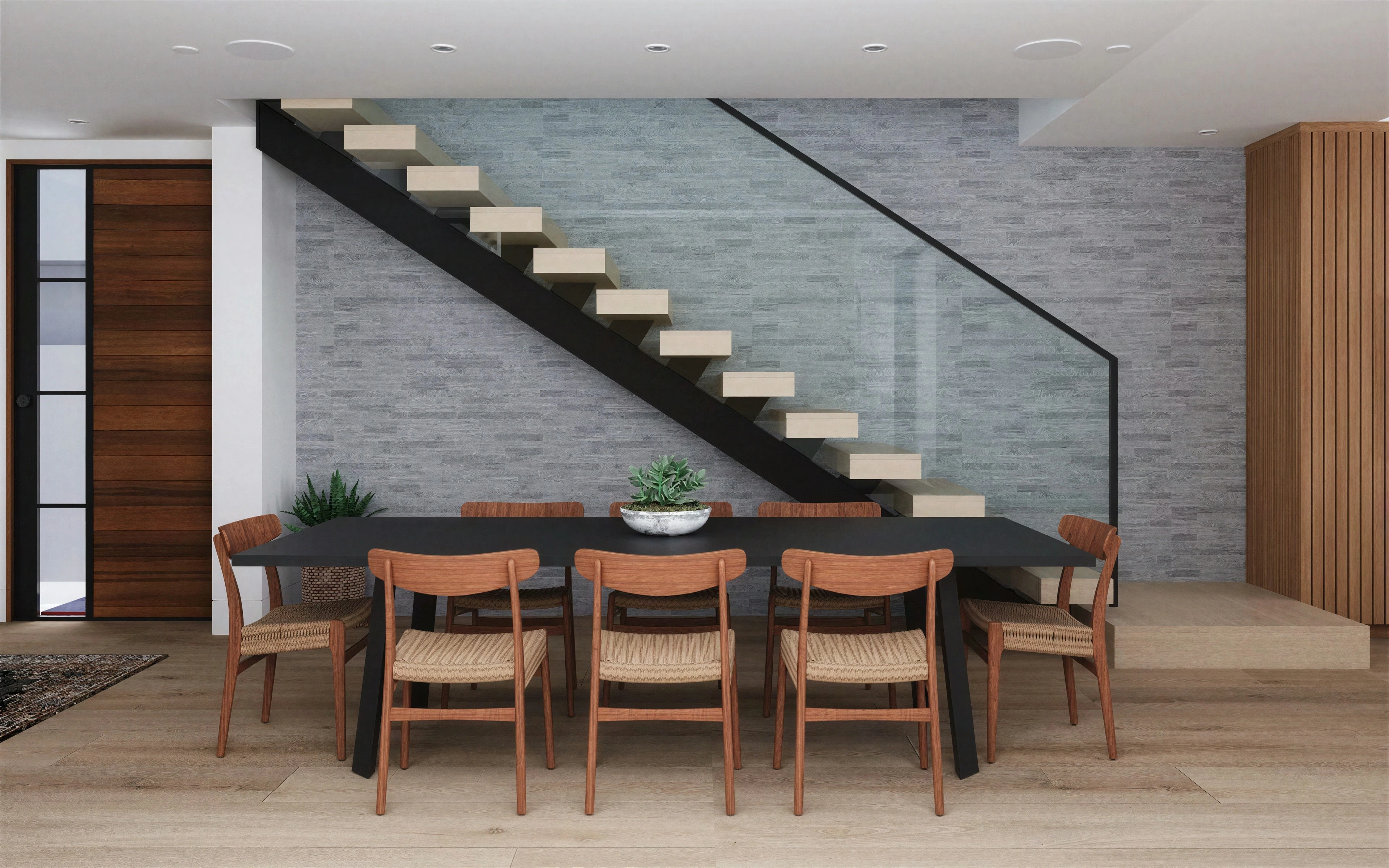 Dining area beneath an open staircase with a slim black railing.