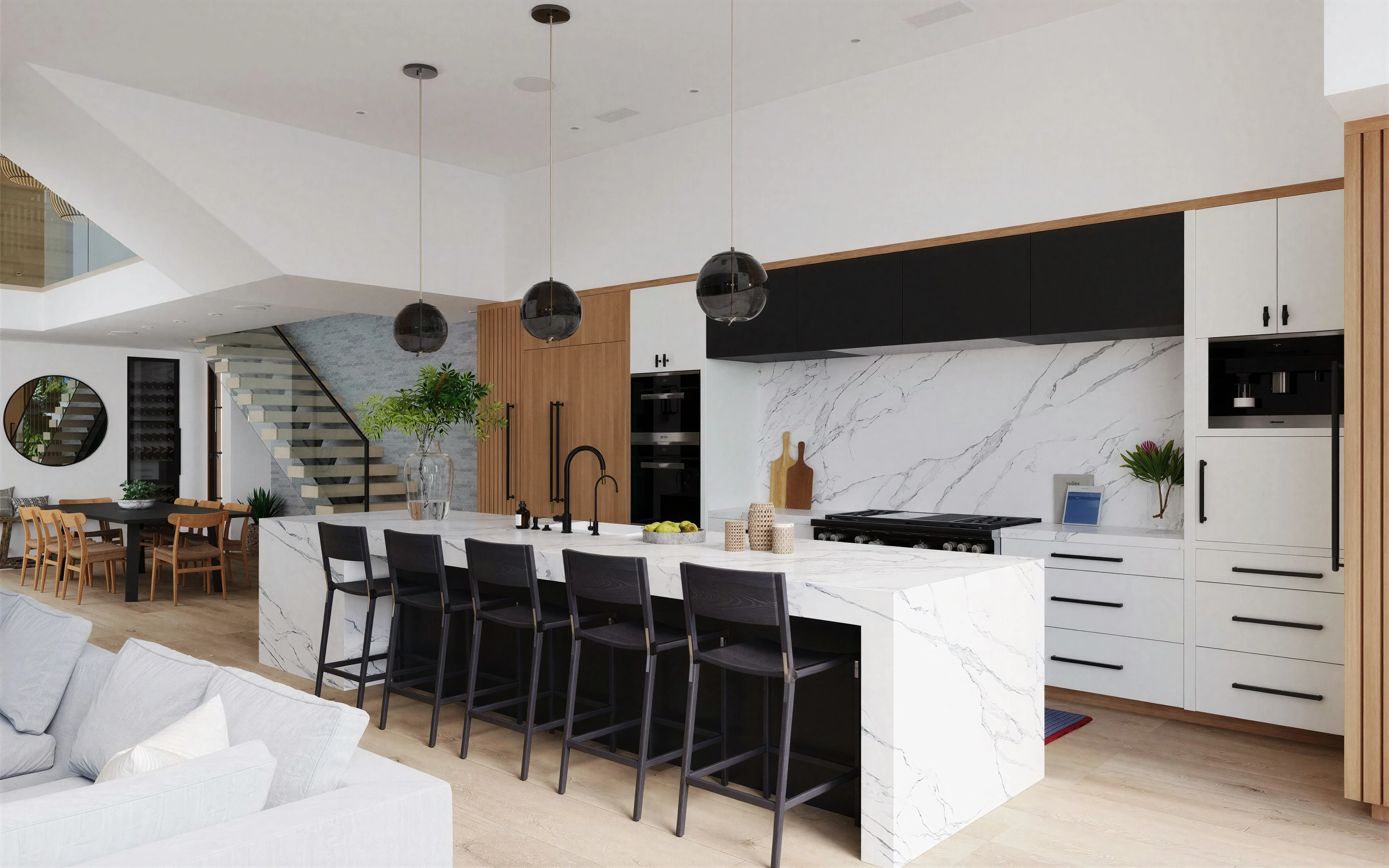 Kitchen and living area with a stone island, black stools and wood cabinetry.