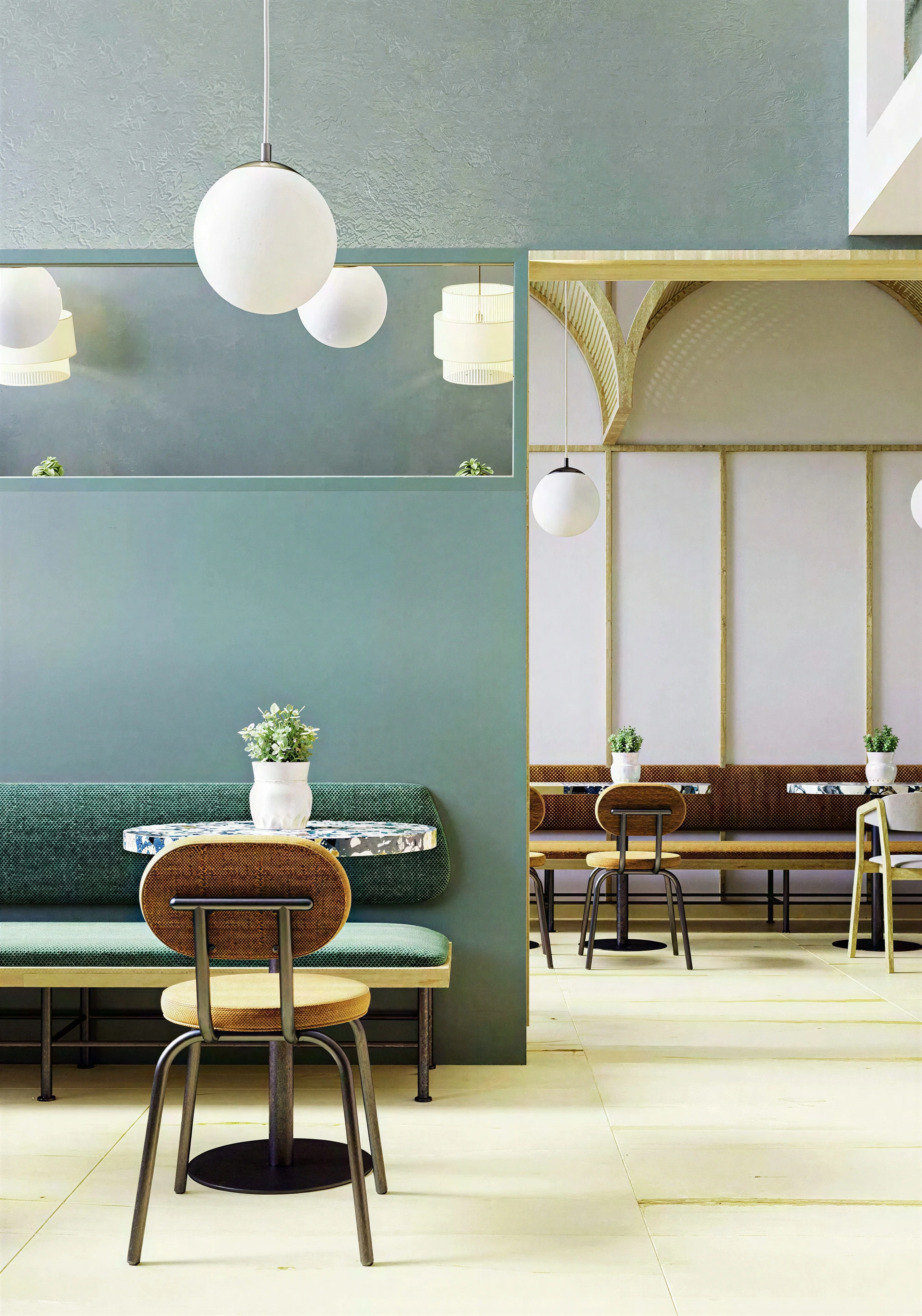 Café table beside teal walls and spherical pendant lights.
