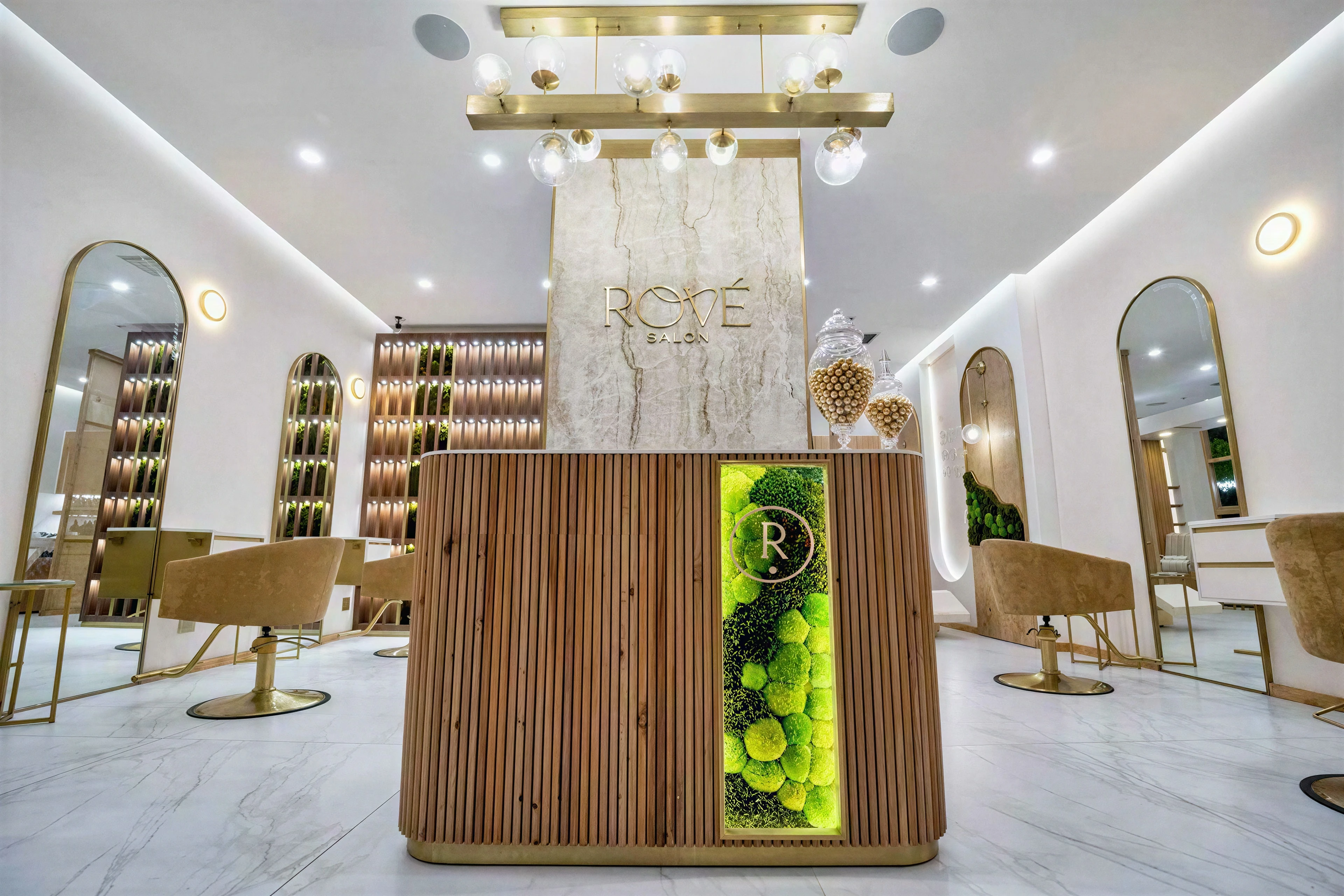 Front view of the reception desk with inset greenery and illuminated signage.