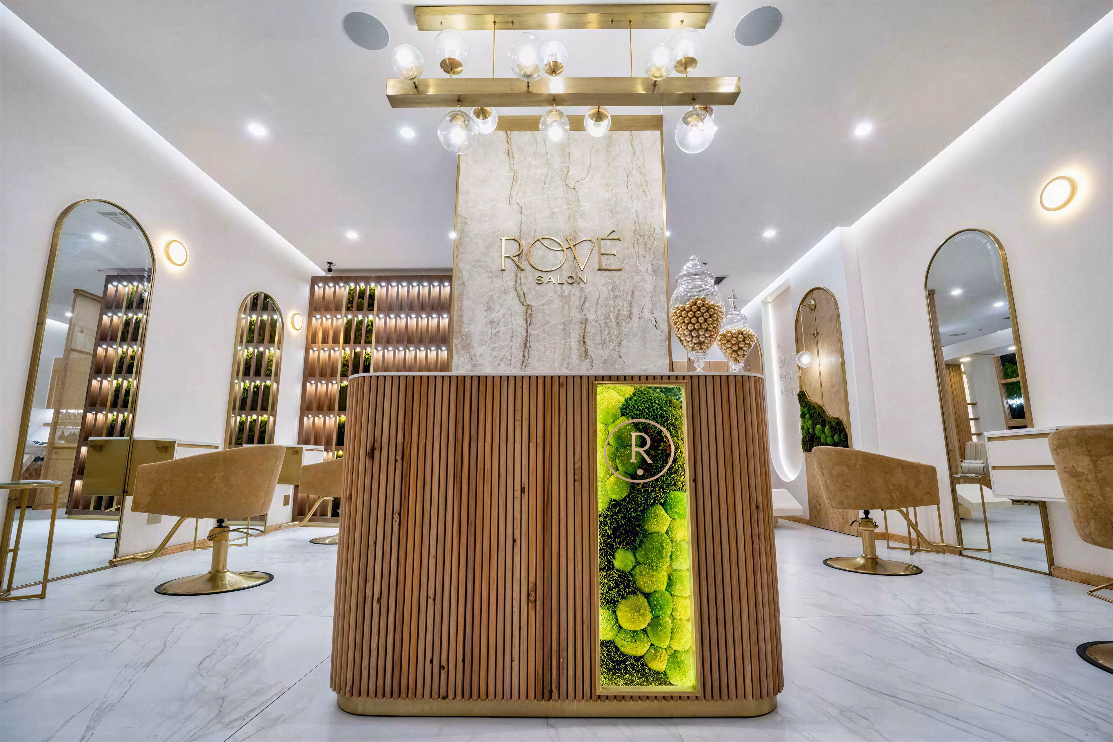 Front view of the reception desk with inset greenery and illuminated signage.