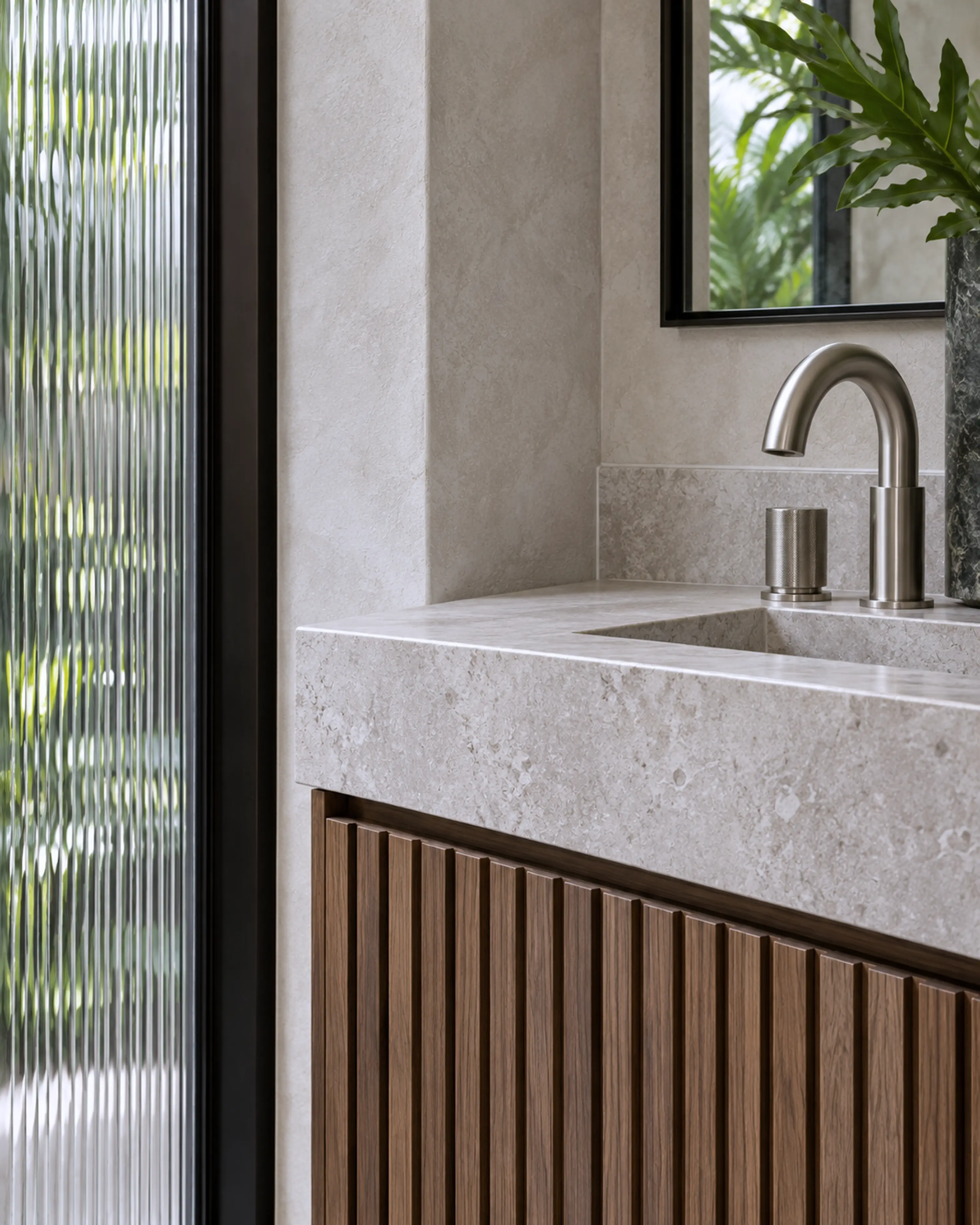 Minimal stone basin and walnut vanity beside a slim black garden window.