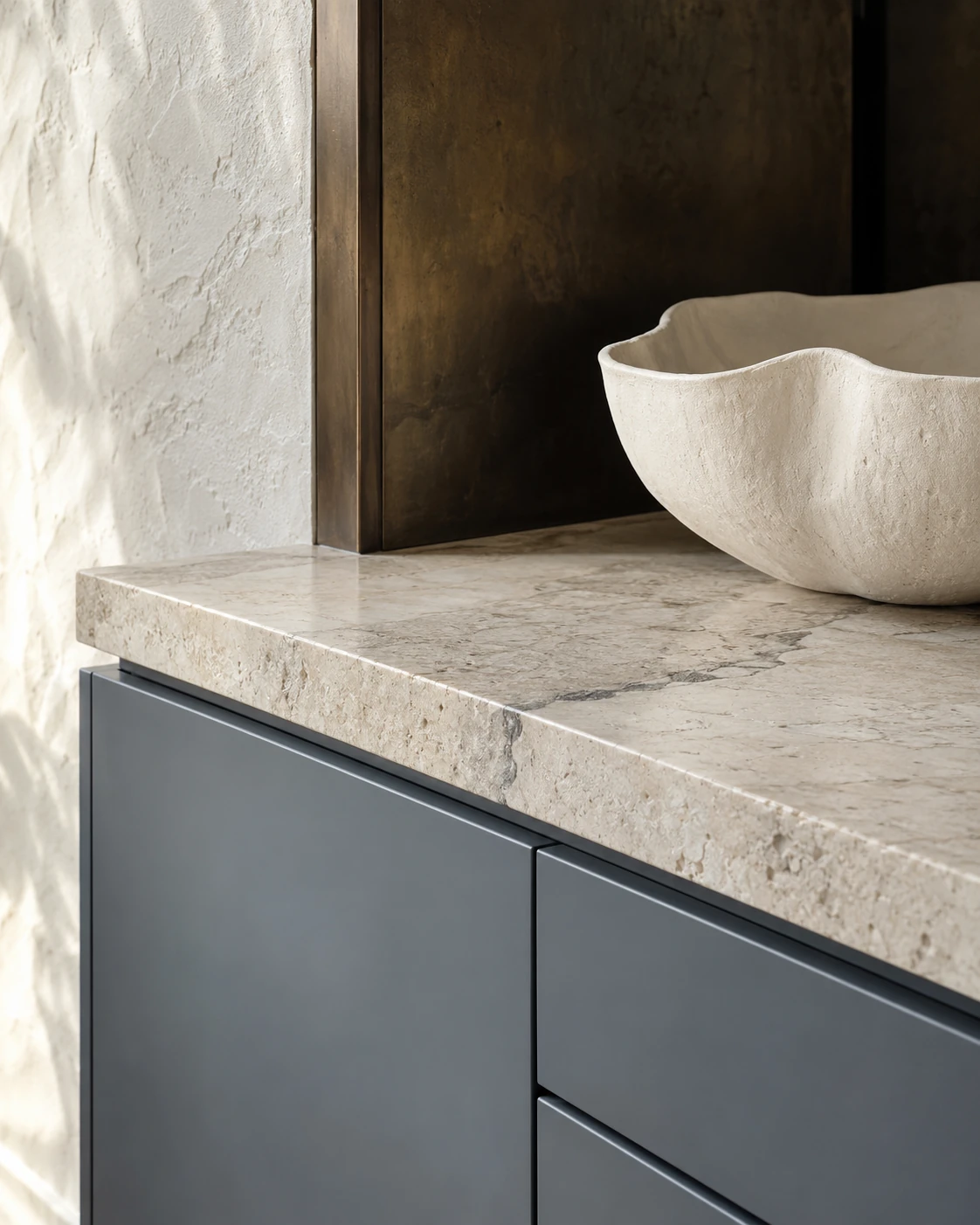 Honed stone, patinated bronze and smoky blue cabinetry detail — RENOVA design concept.