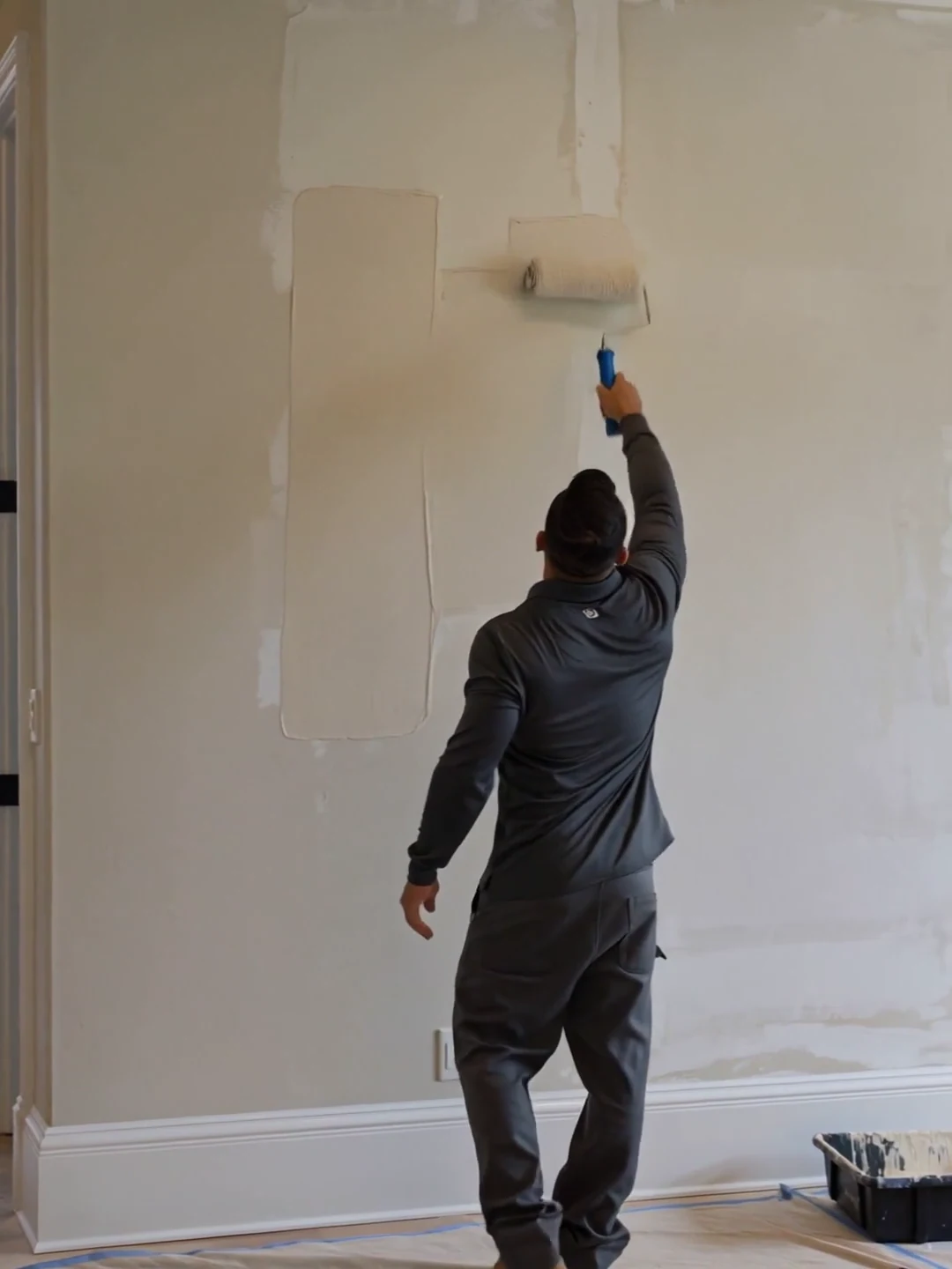 Illustrative scene of a finish painter rolling a warm ivory finish onto a wall in a modern home.